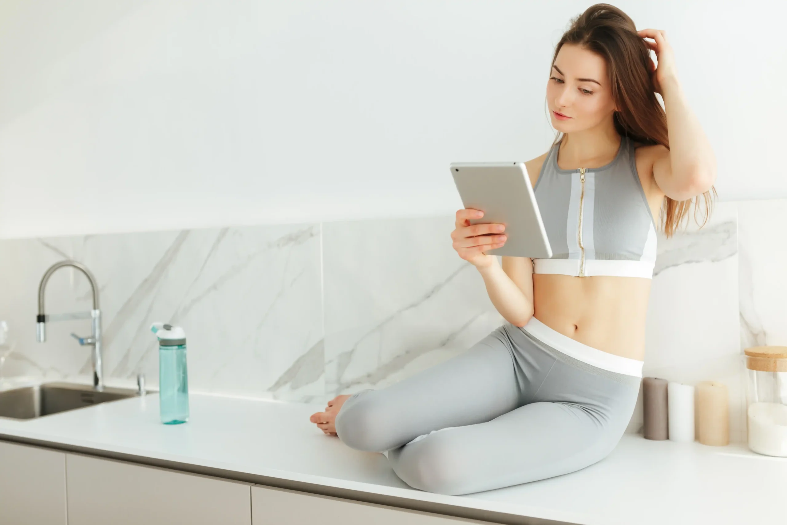 portrait thoughtful lady sporty top leggings sitting kitchen table with tablet hand 11zon portrait thoughtful lady sporty top leggings sitting kitchen table with tablet hand 11zon