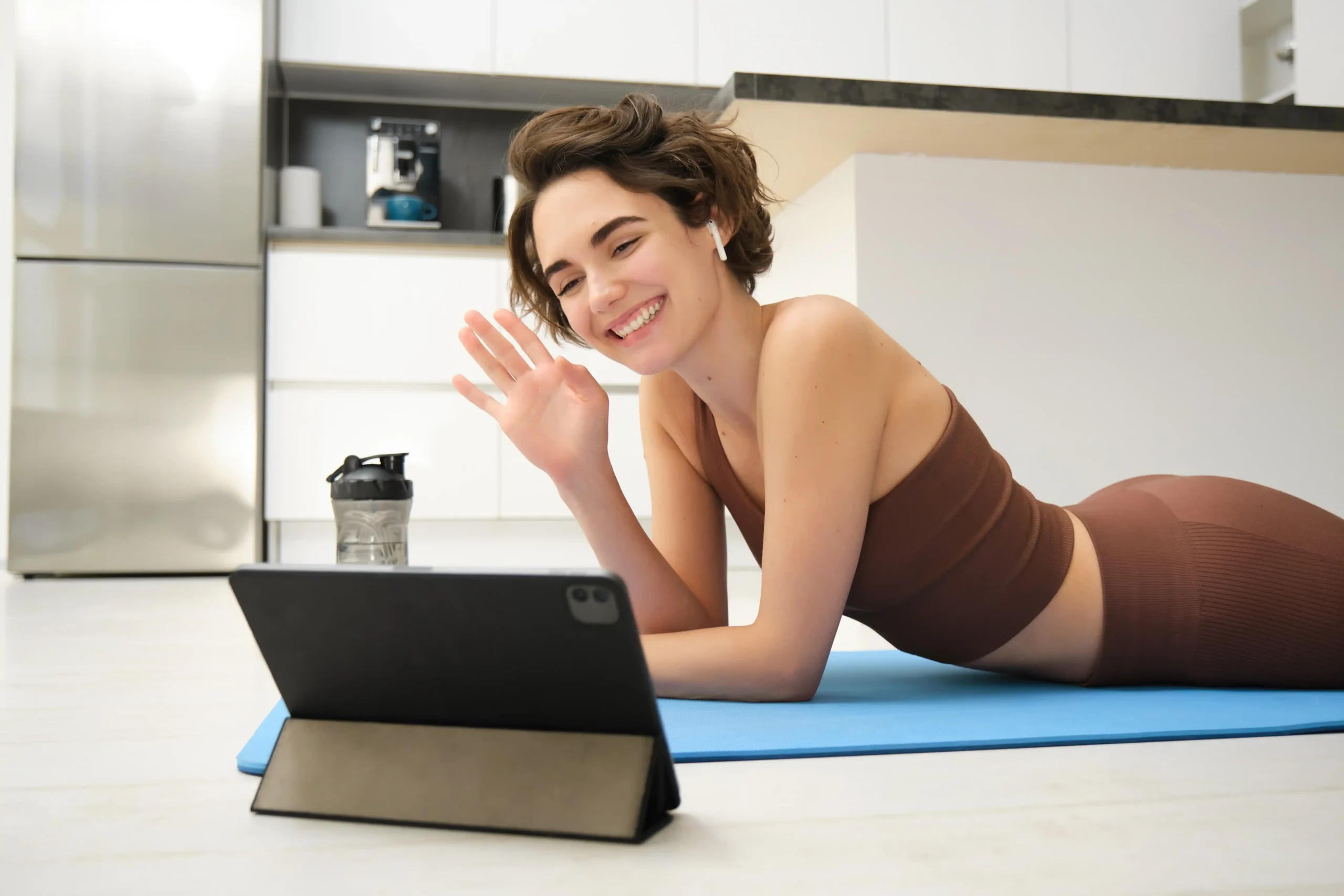 smiling brunette woman sportswear waves hand says hi tablet records video sports blog fitness 11zon smiling brunette woman sportswear waves hand says hi tablet records video sports blog fitness 11zon